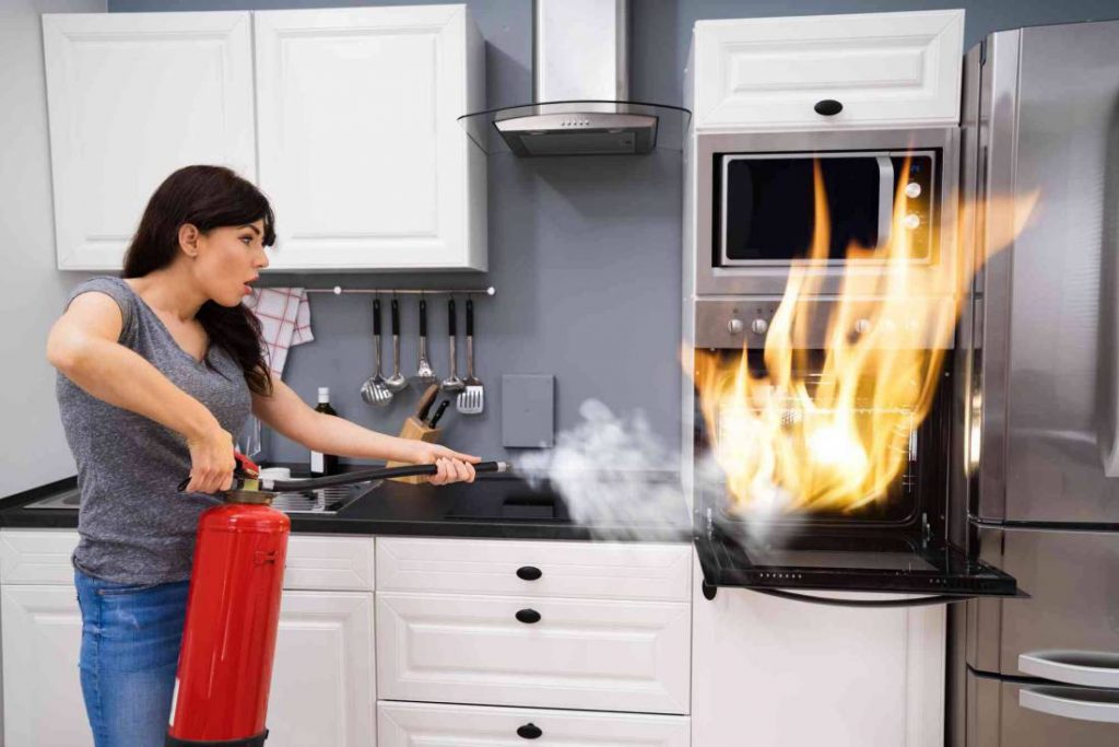 woman putting out fire kitchen compressed